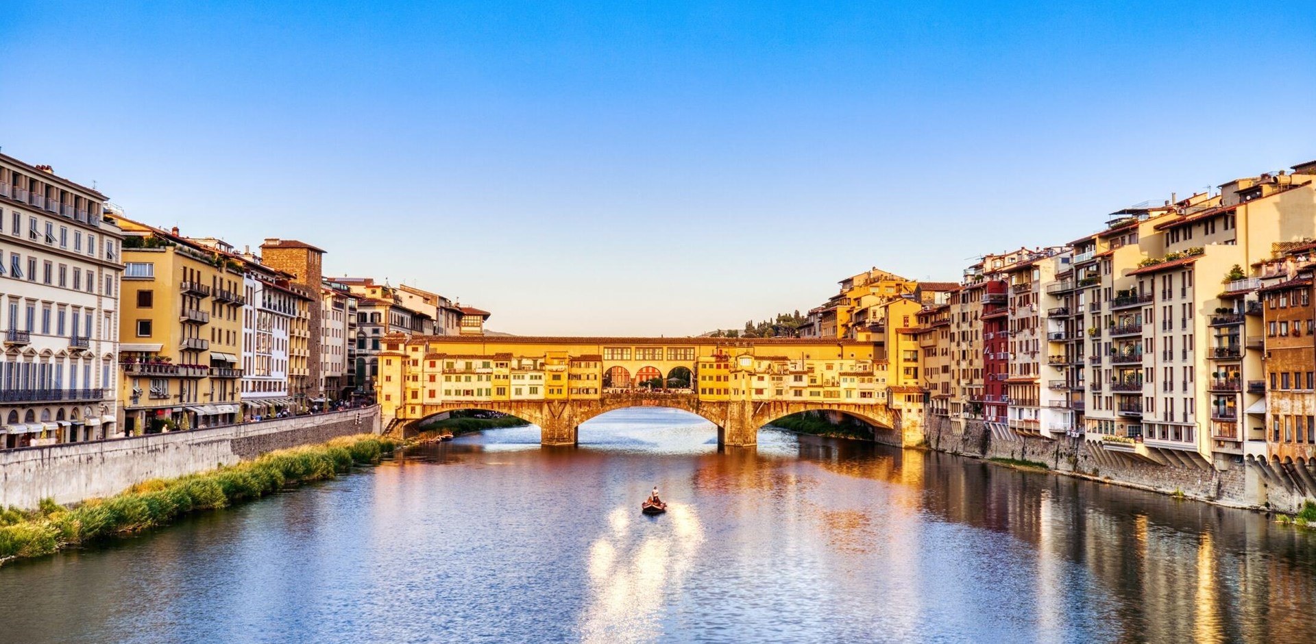 Golden Sunset over Ponte Vecchio Bridge with Traditional Boat on the Arno River, Florence, Italy