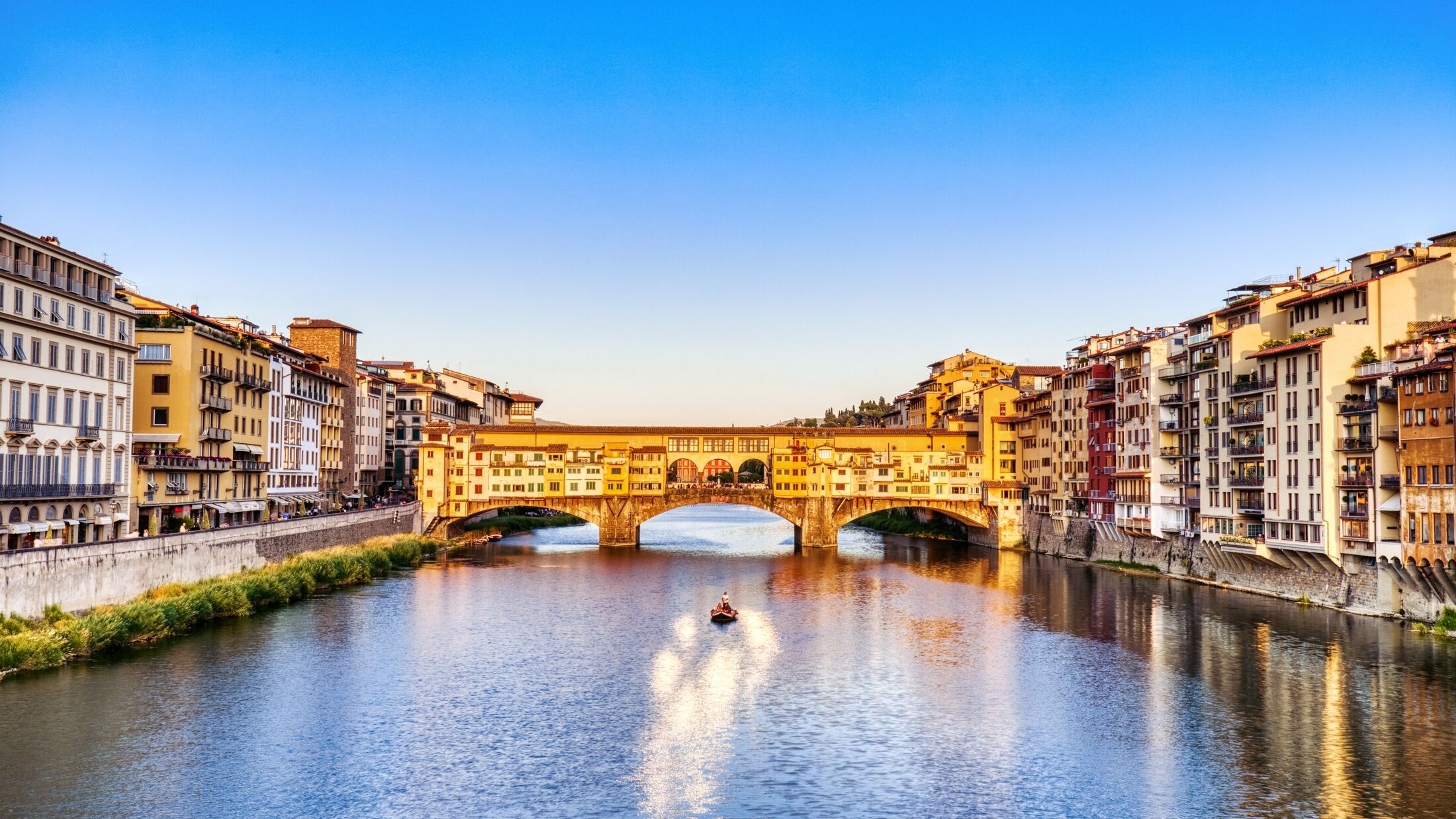 Golden Sunset over Ponte Vecchio Bridge with Traditional Boat on the Arno River, Florence, Italy