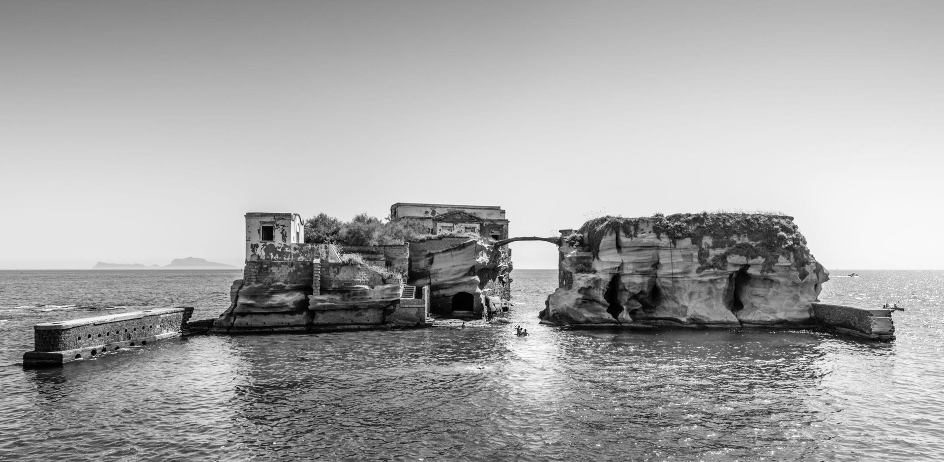 The Gaiola Island, one of the minor islands of Naples, a coastal scenery close to the Underwater Park of Gaiola, a protected marine area. Some boys take a swim by the rocks.