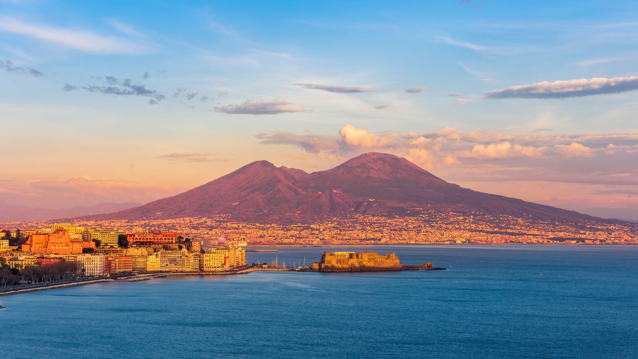 beautiful panorama of volcano Vesuveus from Naples with blue water of sea gulf, majectic mountain and amazing cloudy sunset sky on background