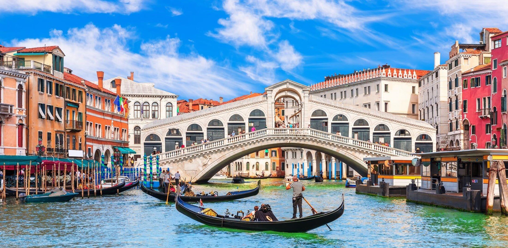 Famous buildings, gondolas and monuments by the Rialto Bridge of Venice on the Grand Canal, Italy