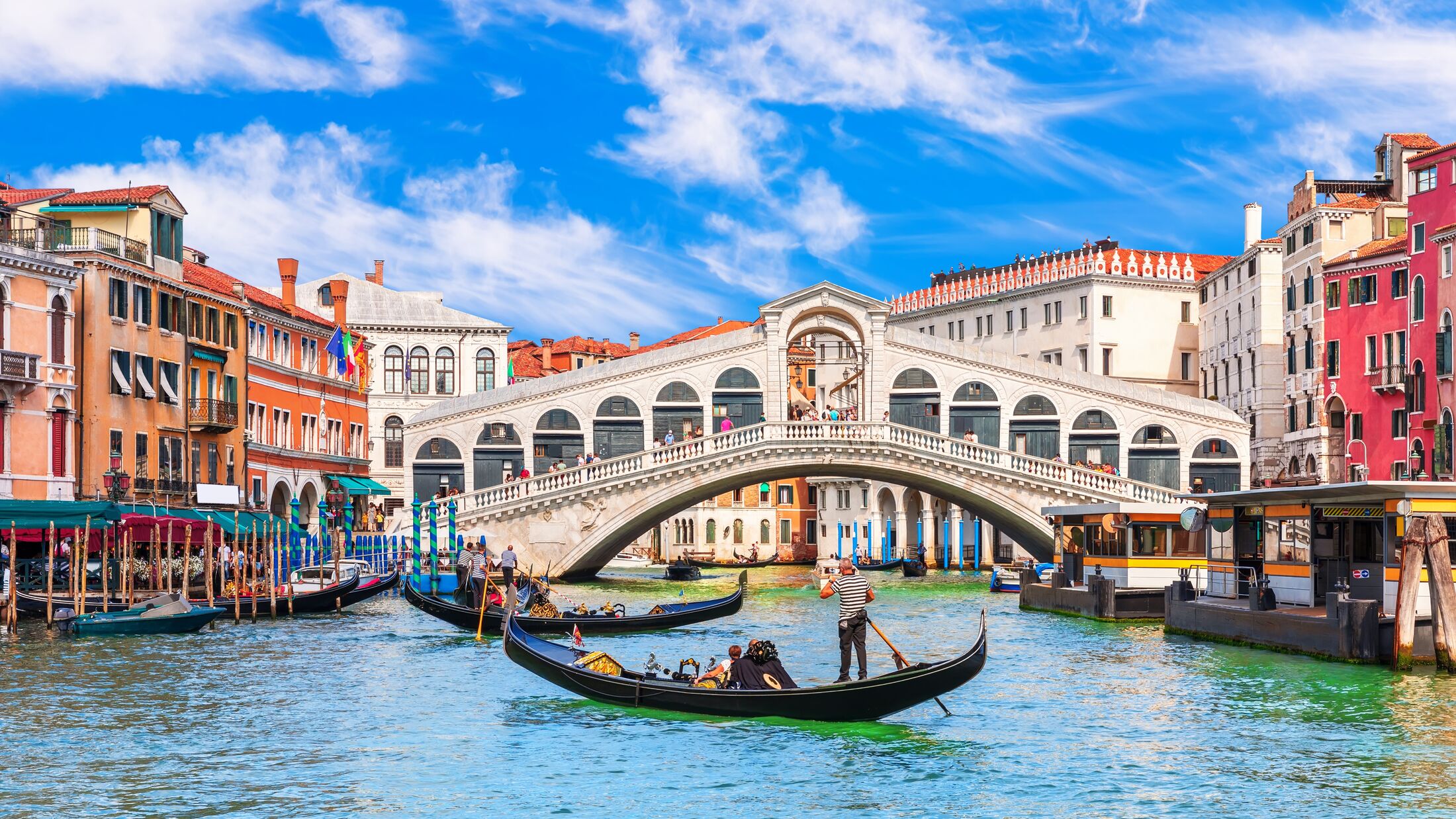 Famous buildings, gondolas and monuments by the Rialto Bridge of Venice on the Grand Canal, Italy