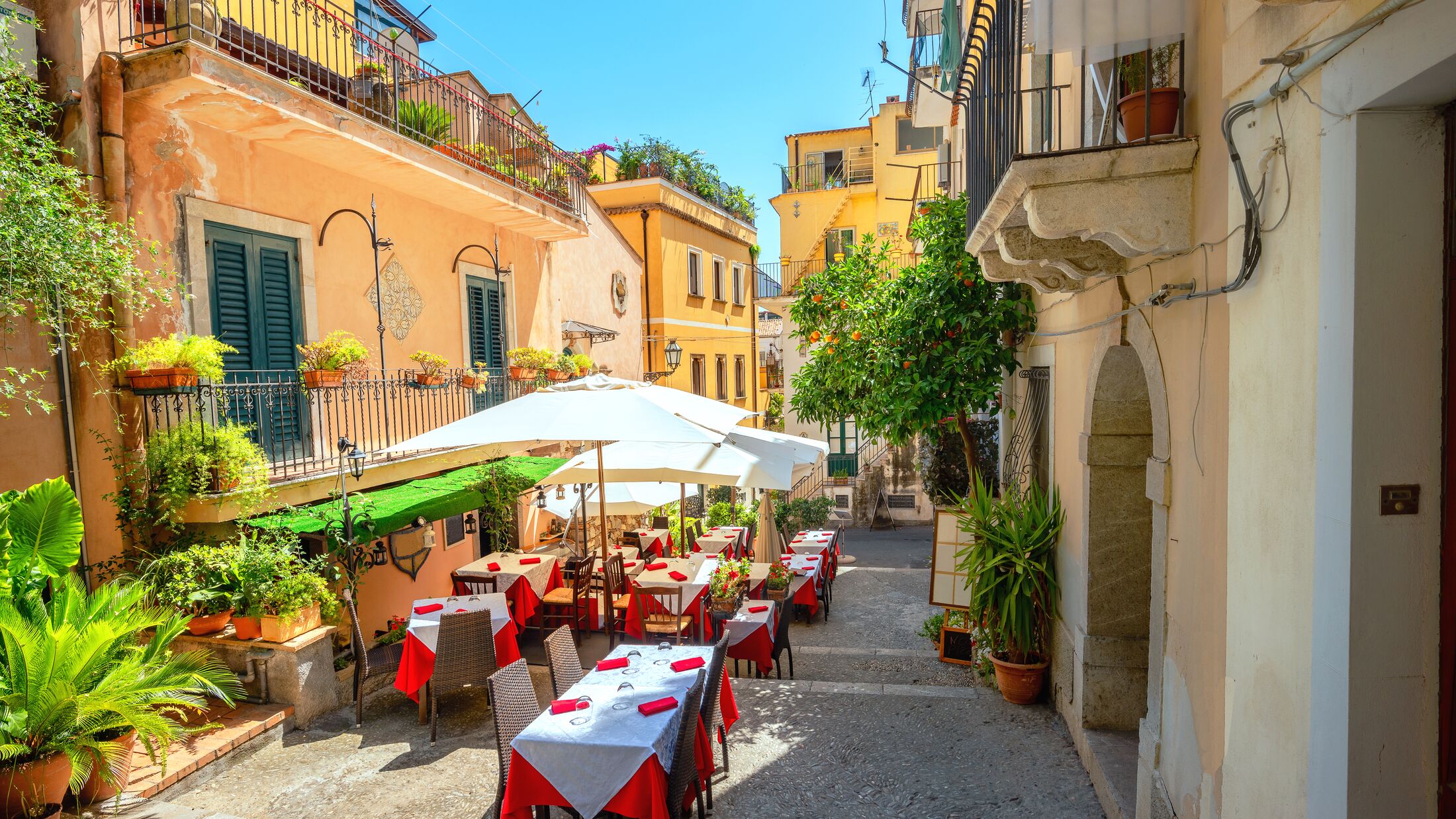 View of colorful narrow pedestrian street with cafe in old town Taormina. Sicily, Italy