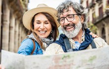 Married couple of tourists sightseeing city street with map - Happy husband and wife enjoying summer vacation together - Touristic life style concept with aged woman and man traveling European city