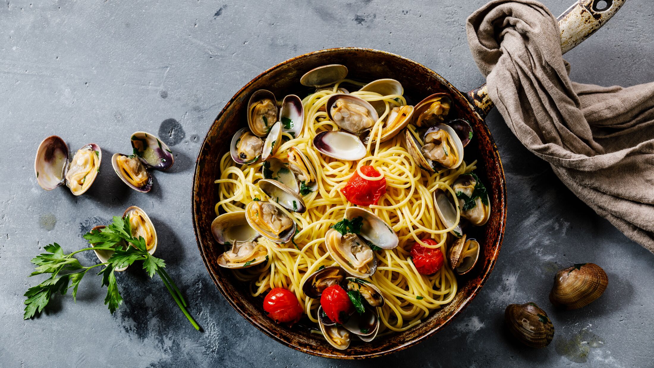 Pasta Spaghetti alle Vongole Seafood pasta with Clams in frying cooking pan on concrete background