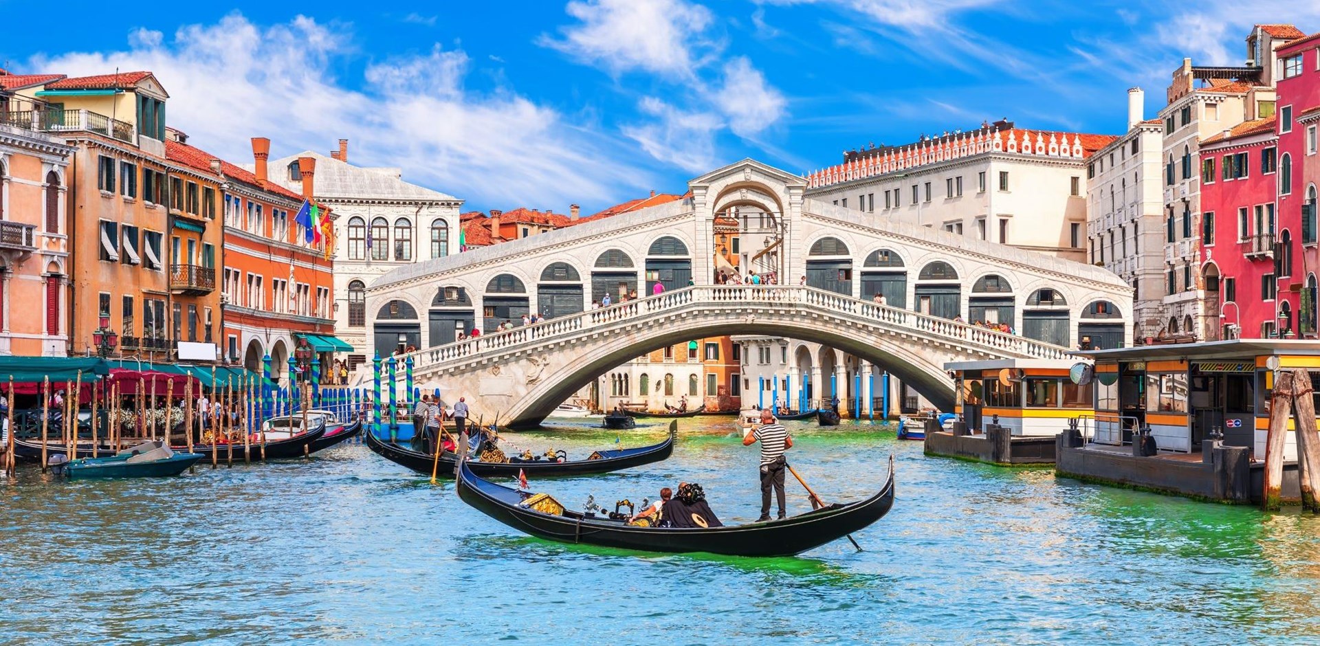 a boat is docked next to a body of water with Rialto Bridge in the background